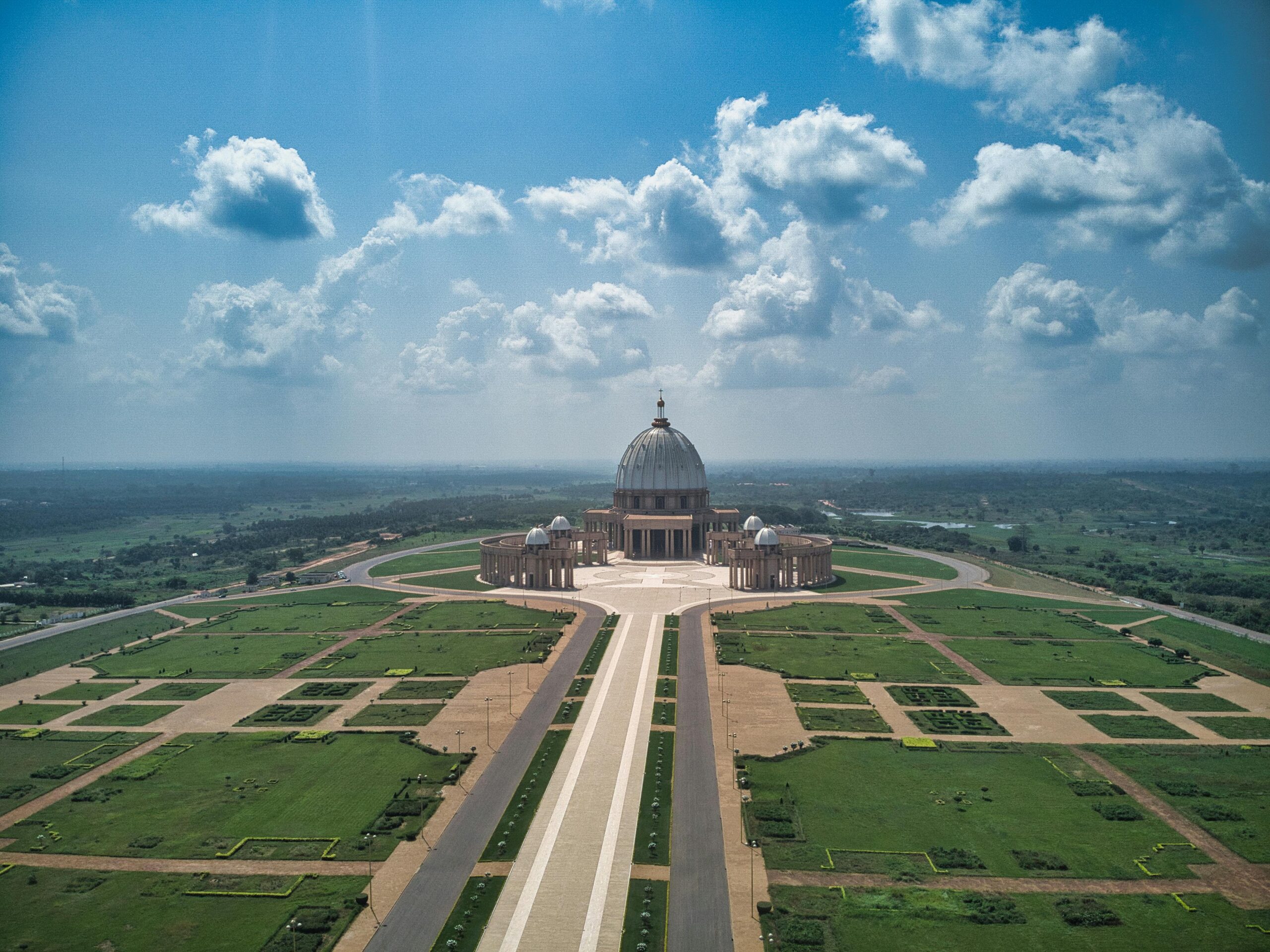 Aerial view of the Basilica of Our Lady of Peace in Yamoussoukro under a bright sky.